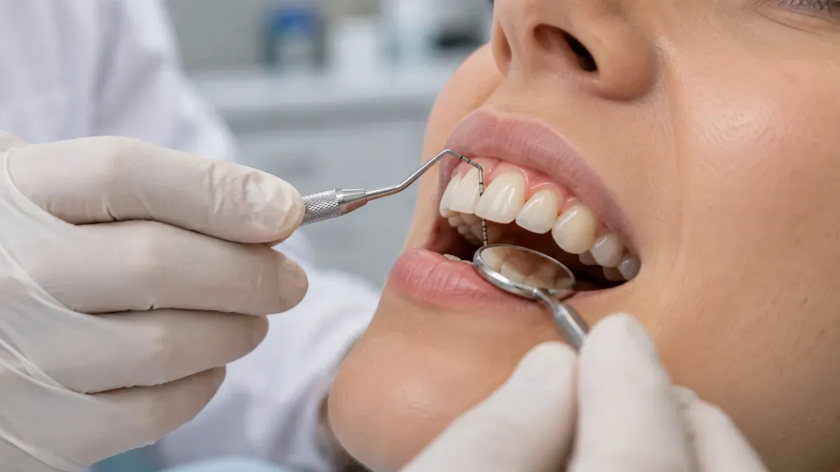 Periodontoloji polikliniğinde diş hekiminin periodontal sondla diş eti çevresini değerlendirdiği ve hastanın dişlerinin yakın açıdan görüldüğü sade klinik sahne